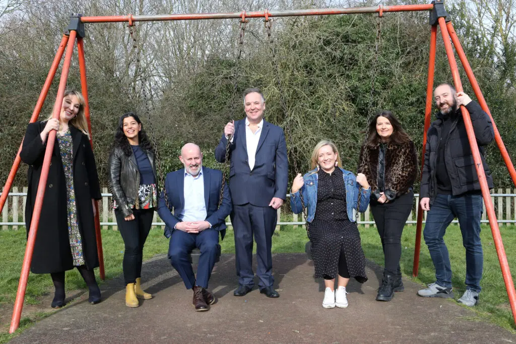 7 Qualis employes on a swing set in a playground