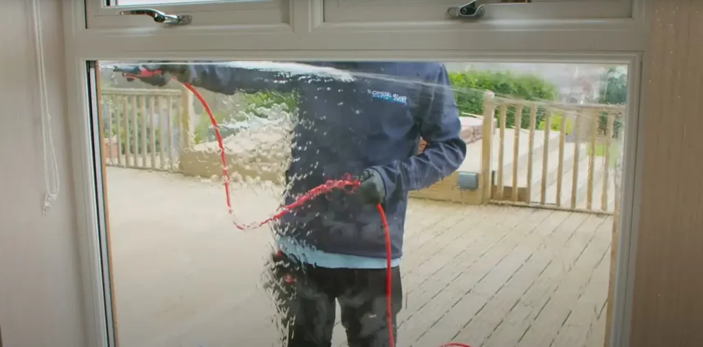 YouTube screenshot of a person using a hose to clean a window