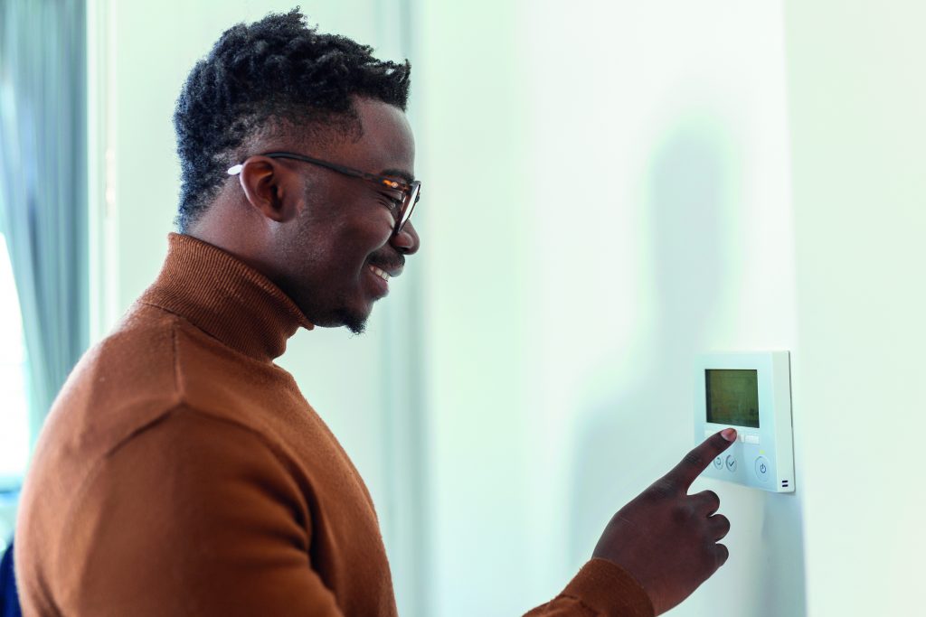 Man stands in front of wall thermostat