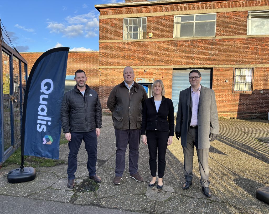 Three men and a woman stand next to a derelict looking building
