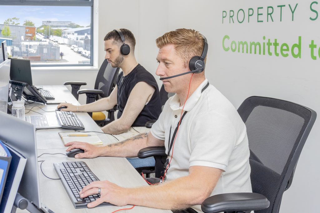 Two men seated at a desk wearing headsets