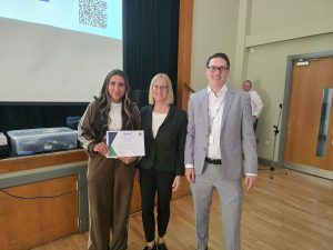 Woman holds certificate next to a woman and another man