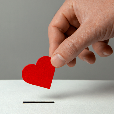 hand placing a heart into a donation box