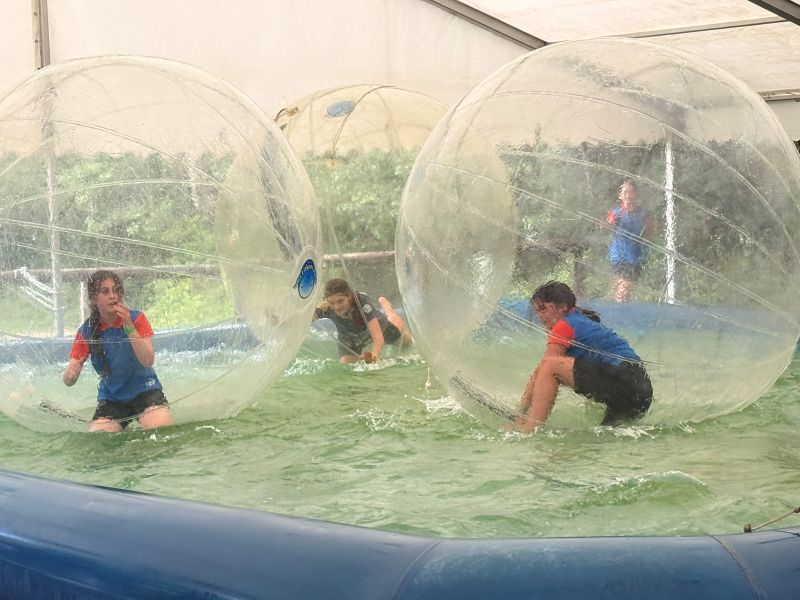 children from roydon guides play in giant inflatable balls that float on water